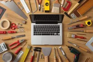 Drie geweldige gratis marketing tools 1 Laptop on a work table with DIY and construction tools all around top view hobby and crafts concept