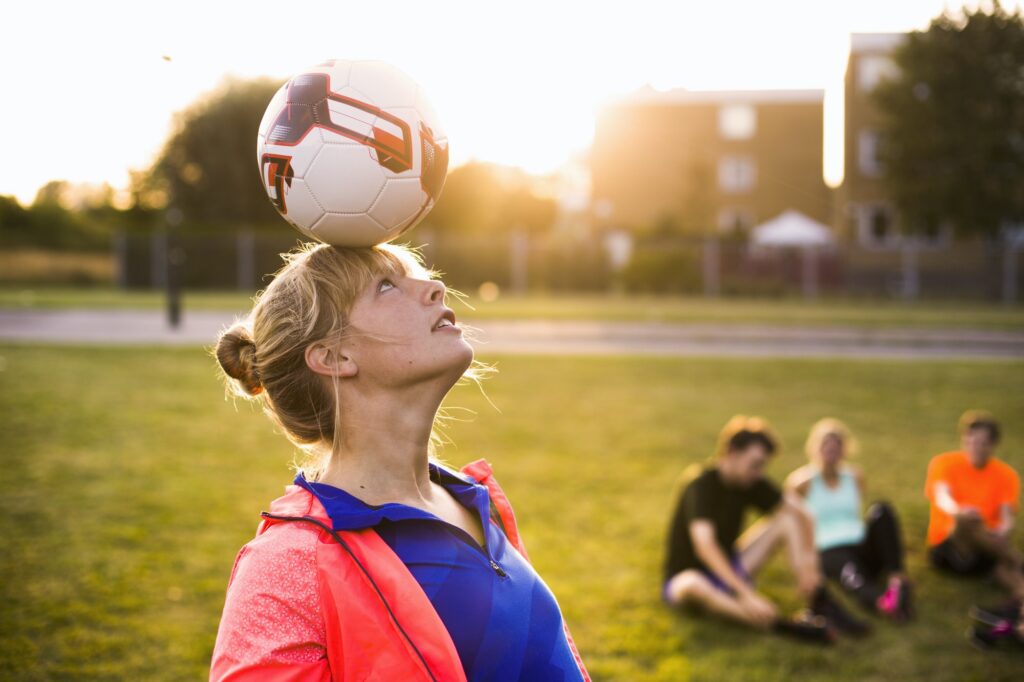 Sporty woman balancing ball on head at park