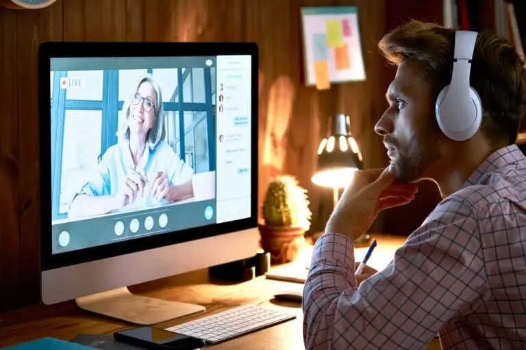 Serious male student wearing headphones taking online course, watching webinar.