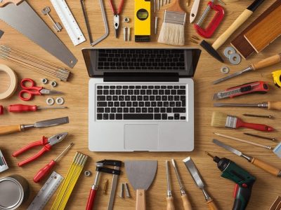 Laptop on a work table with DIY and construction tools all around top view hobby and crafts concept