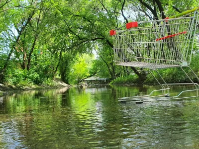 a cart from a supermarket stands in a river against the backdrop of a beautiful landscape
