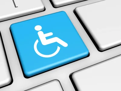 Digitale toegankelijkheid verbeeld als een knop met een persoon in een rolstoel op een toetsenbord