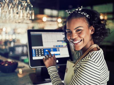 smiling-african-waitress-using-a-restaurant-point-of-sale-terminal